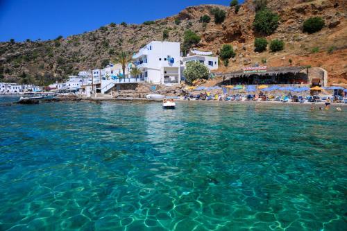 a view of a beach with blue water and buildings at Molos Apartments in Loutro