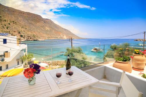 a table with a bottle of wine and flowers on a balcony at Molos Apartments in Loutro