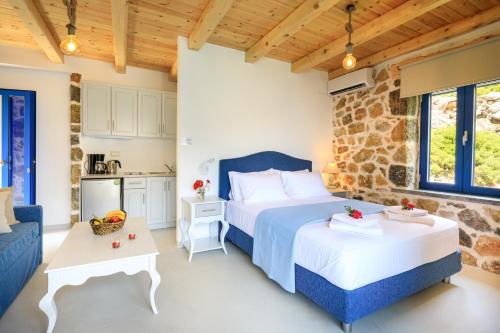 a bedroom with two beds and a stone wall at Molos Apartments in Loutro