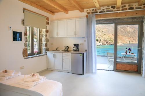 a kitchen with white cabinets and a view of the ocean at Molos Apartments in Loutro