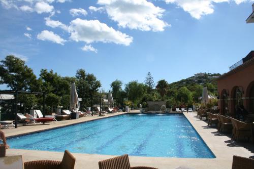 a pool at a resort with lounge chairs and umbrellas at Hotel MR Les Rotes in Denia