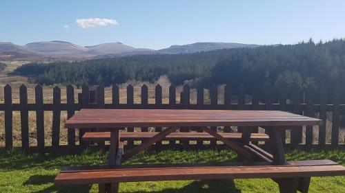 a wooden picnic table in front of a wooden fence at Riverside in Skeabost