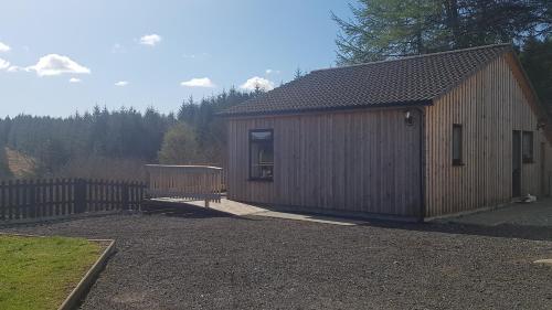 a wooden shed with a bench next to a fence at Riverside in Skeabost