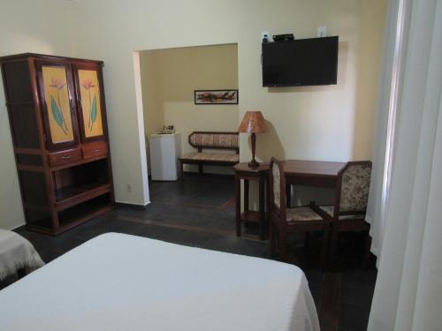 ein Hotelzimmer mit einem Bett, einem Schreibtisch und einem TV in der Unterkunft Alfenas Palace Hotel in Alfenas