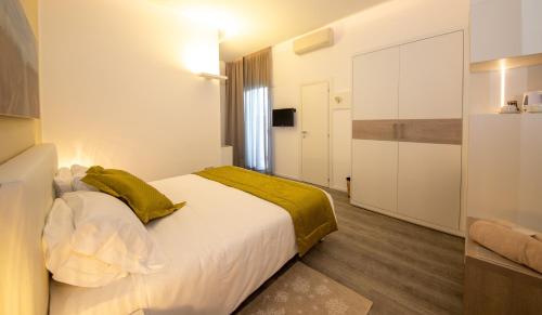a bedroom with a large white bed with a yellow blanket at Hotel Aurora in Lido di Jesolo