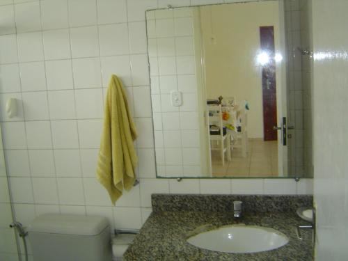 y baño con lavabo, espejo y aseo. en Condomínio Villa Nova, en Porto Seguro