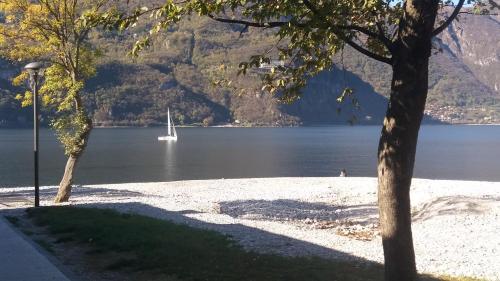 a boat in the water next to a beach at Casa vacanze da Carla in Abbadia Lariana