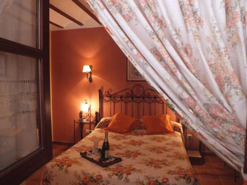 a bedroom with a bed with a curtain and a bottle of wine at Hotel Rural Posada Los Caballeros in Almagro