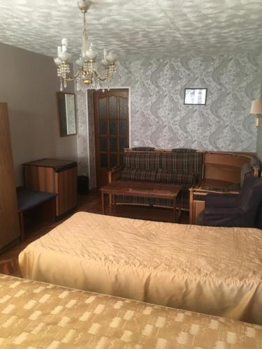 a bedroom with a bed and a couch and a chandelier at Apartment Vash Dom in Murmansk