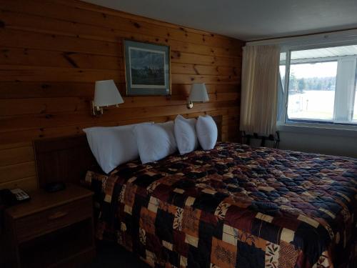 1 dormitorio con 1 cama con pared de madera en Clark's Beach Motel, en Old Forge