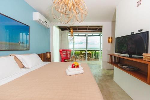 a bedroom with a large bed with a television and a chandelier at Manati in Barra Grande