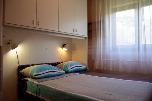sypialnia z łóżkiem z dwiema poduszkami i oknem w obiekcie Apartmani Blaslov w mieście Kali