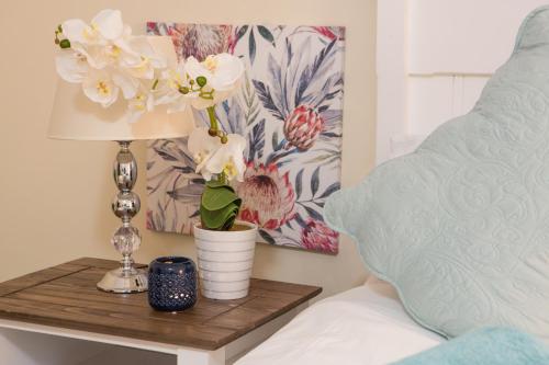 a bedside table with a lamp and flowers on it at The Living Collective - The Gates in Hilton