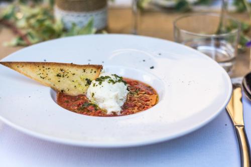a white plate with a bowl of soup and a slice of pizza at Le Mas de l'Espérance - Chambres d'hôtes de Prestige in Garons