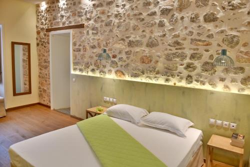 a bedroom with a bed and a stone wall at Manolia in Hydra