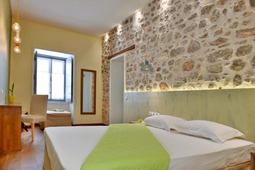 a bedroom with a bed and a stone wall at Manolia in Hydra