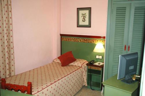 a small bedroom with a bed and a desk with a television at Hotel Restaurante Logasasanti in Andújar