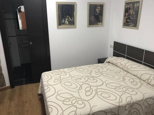Un dormitorio con una cama y dos cuadros en la pared. en kilometro 15, en Amenal