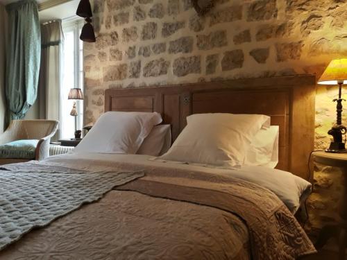 - une chambre avec un grand lit et un mur en pierre dans l'établissement Chateau Le Colombier, à Brévands