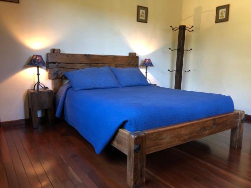 a bedroom with a wooden bed with blue sheets and two lamps at Arco Iris Lodge in Monteverde Costa Rica