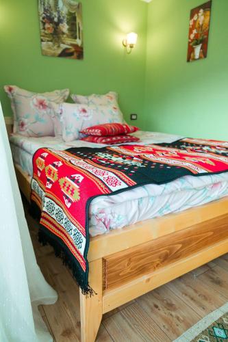 a bed with a colorful blanket on top of it at agropensiunea CASA NICA in Mărgineni
