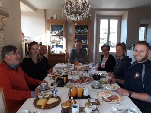 een groep mensen die rond een tafel zitten met eten bij Chateau Le Colombier in Brévands