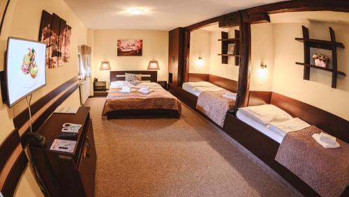 a room with two beds and a flat screen tv at Hotel Kaskada in Poprad