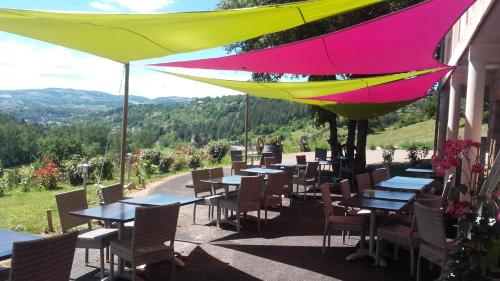 Montrodat的住宿－Lauz'oustal，餐厅配有桌椅,位于色彩缤纷的雨伞下