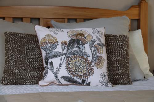 almohada con motivos florales en una cama en The Point B&B, en Kaikoura