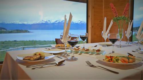 a table with plates of food and glasses of wine at El Arrayan in Puerto Guadal