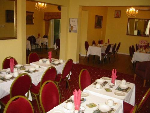 a dining room with white tables and red chairs at The Langham Hotel in Northampton