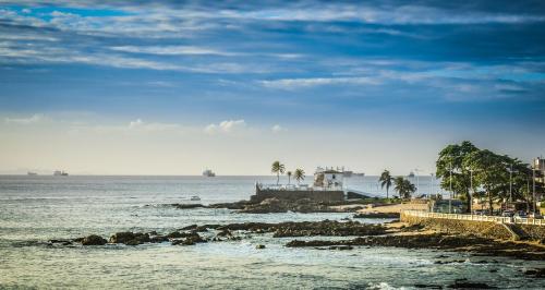 a view of the ocean with palm trees and a pier at Hit Hotel in Salvador
