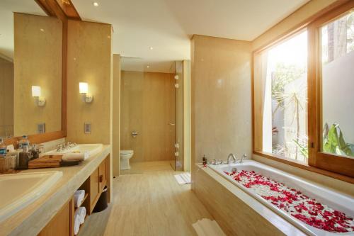 La salle de bains est pourvue d'une grande baignoire et d'une grande fenêtre. dans l'établissement KoenoKoeni Villa, à Seminyak