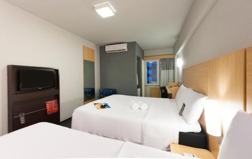 a hotel room with two beds and a tv at ibis Fortaleza Praia de Iracema in Fortaleza