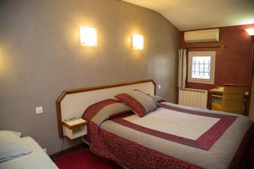 a small bedroom with a bed and a window at Logis Hôtel La Farigoule in Sainte-Cécile-les-Vignes