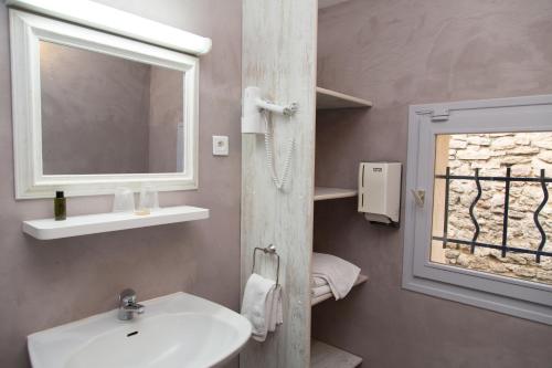 a bathroom with a sink and a mirror and a window at Logis Hôtel La Farigoule in Sainte-Cécile-les-Vignes