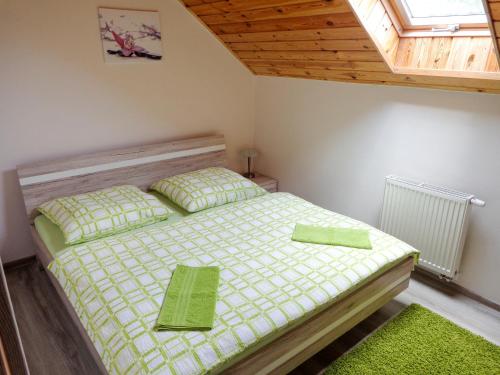 Schlafzimmer mit einem Bett mit grüner Bettwäsche und einem Fenster in der Unterkunft Apartman Grena - GRENA sk in Štôla