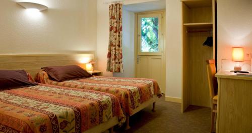 a hotel room with two beds and a window at Hotel De La Poste in Saint-Martin-sous-Vigouroux