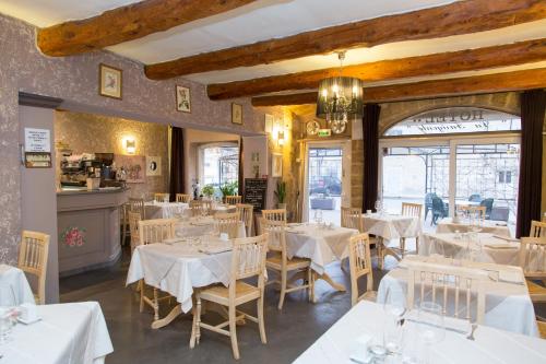 une salle à manger avec des tables et des chaises blanches dans l'établissement Logis Hôtel La Farigoule, à Sainte-Cécile-les-Vignes