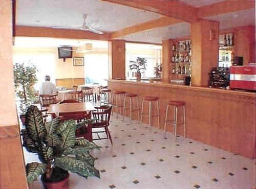 un restaurante con bar, mesas y sillas en Hotel Iris en Benidorm