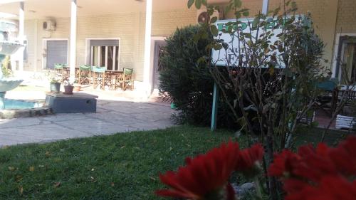a house with a yard with flowers and a patio at Hotel Nuevo Fatica in Villa Carlos Paz