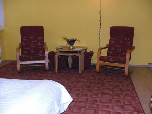 a bedroom with two chairs and a table and a bed at Dom Gościnny Pod Brzozami in Poznań