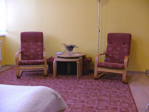 a room with two chairs and a table and a bed at Dom Gościnny Pod Brzozami in Poznań