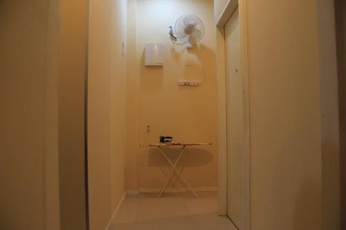Habitación con mesa y ventilador en la pared. en Prima B&B Hostel, en Sandakan
