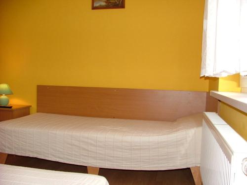 a bed in a room with a yellow wall at Dom Gościnny Pod Brzozami in Poznań