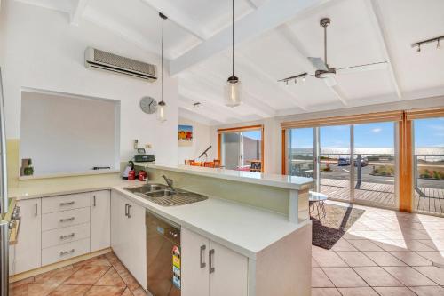 a kitchen with white cabinets and a view of the ocean at Queensland South - Aldinga Beach - C21 SouthCoast Holidays in Aldinga Beach