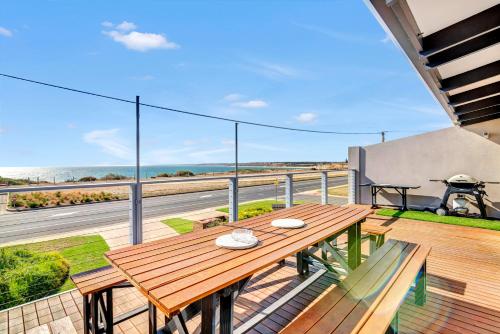 a wooden table on a balcony with a view of the ocean at Queensland South - Aldinga Beach - C21 SouthCoast Holidays in Aldinga Beach