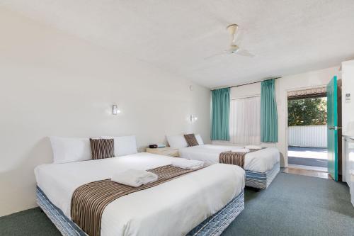 Habitación de hotel con 2 camas y ventana en Coffs Harbour Pacific Palms Motel, en Coffs Harbour