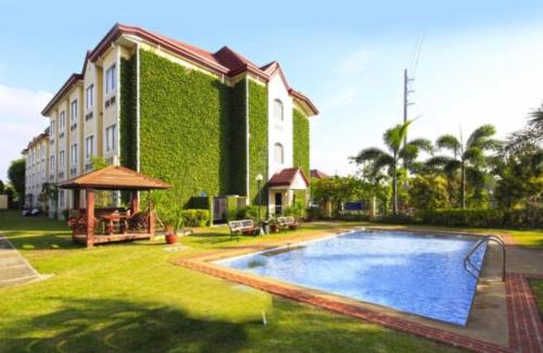 a large building with a swimming pool in the yard at Microtel by Wyndham Batangas in Santo Tomas