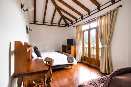 a bedroom with a bed and a desk and a window at Hotel El Giro in Villa de Leyva
